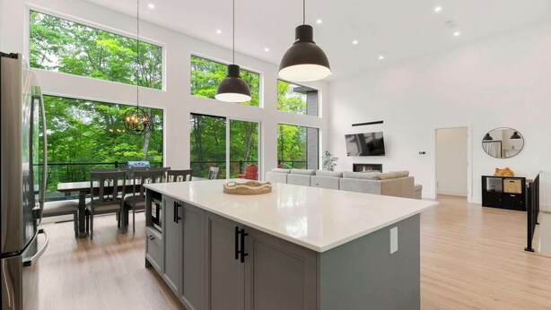 Una cocina moderna con una isla grande, comedor y sala de estar con televisor y chimenea.
