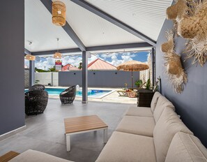 Une terrasse extérieure avec une piscine, des sièges et un parasol en chaume.