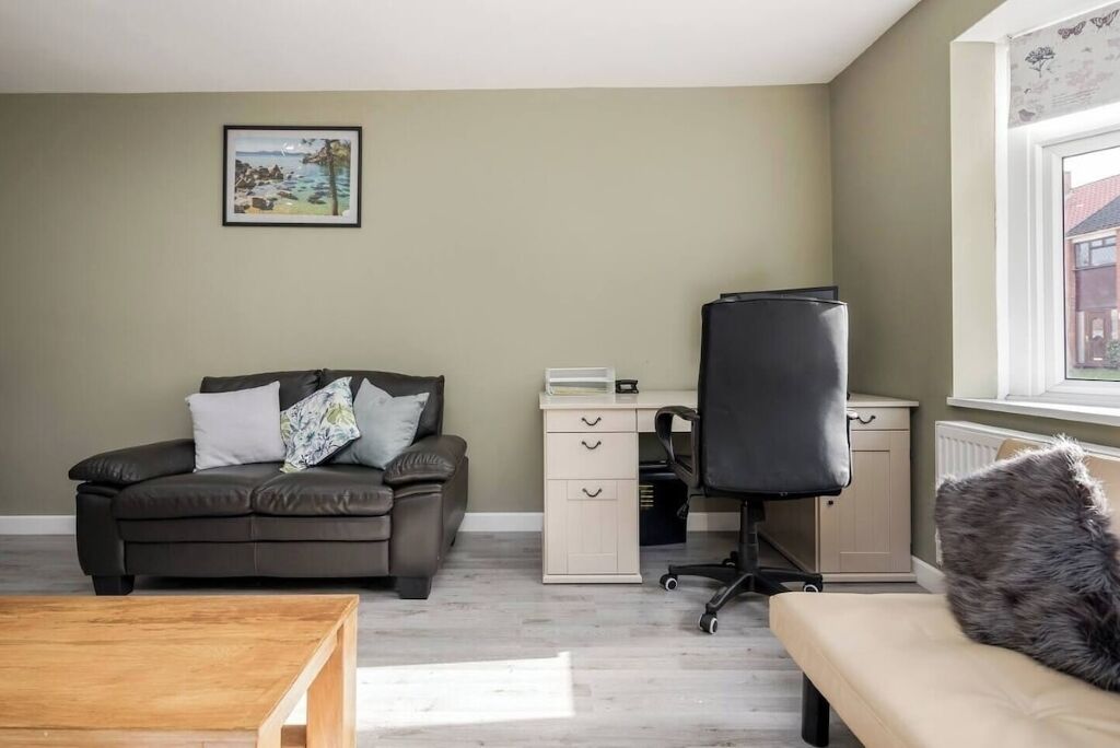 A room with a sofa, a desk, a chair, and a window.