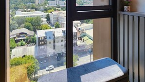A modern room with large windows offering a city view, a bench, and built-in shelves with lighting. - Diamond Residences 2bd 2bth 11th fl. Lux Apt w/ Free Parking (Skopje)