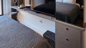 A modern bedroom with a large bed, a TV, and built-in storage. - Diamond Residences 2bd 2bth 11th fl. Lux Apt w/ Free Parking (Skopje)