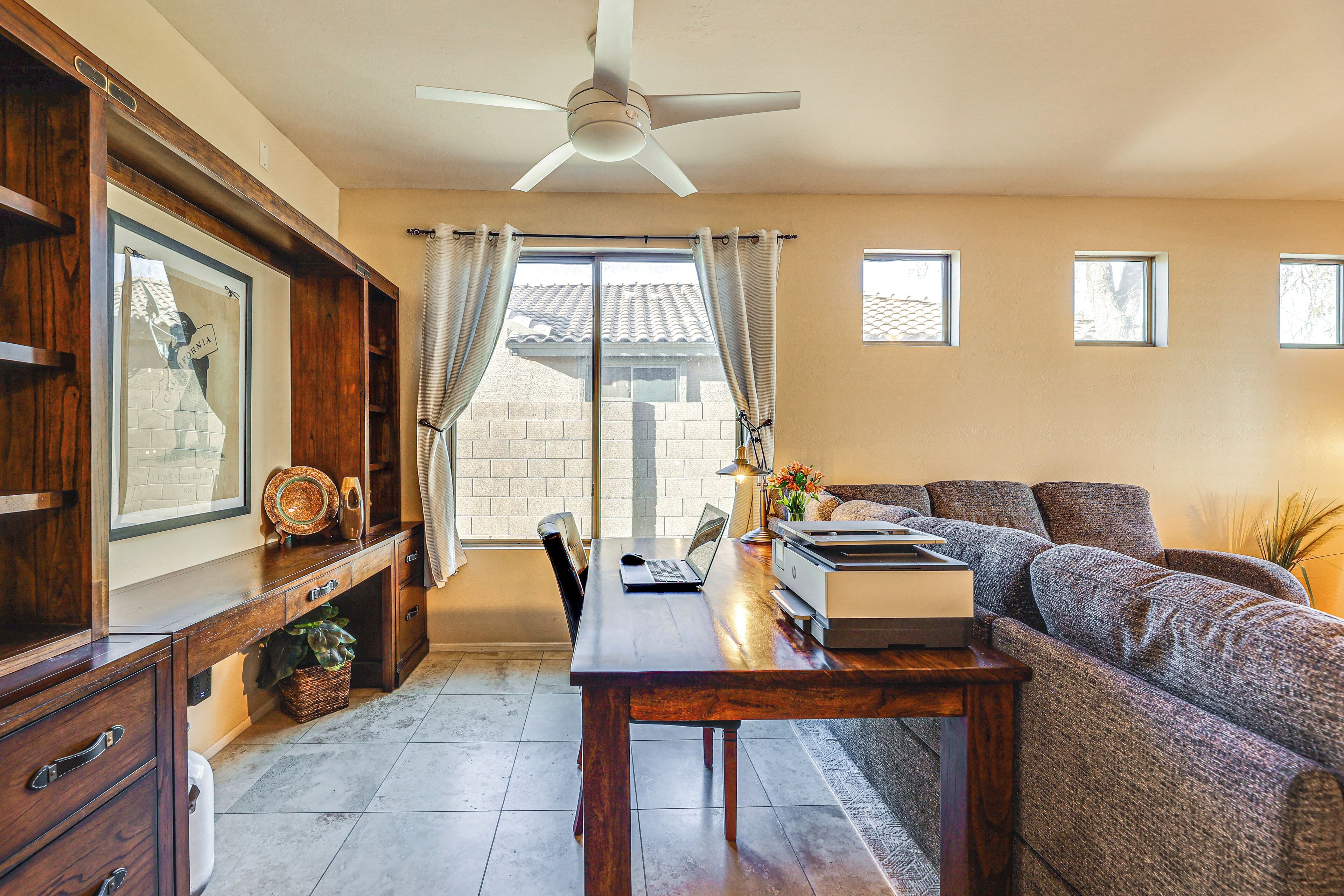A spacious living area with a wooden dining table, a sofa, and a ceiling fan.