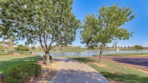 A park with a paved walkway, trees, and a lake. - Hot Tub & Heated Pool: Home in Estrella Mtn Ranch (Goodyear)