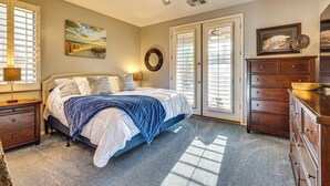 A bedroom with a bed, a dresser, a ceiling fan, and a painting on the wall. - Hot Tub & Heated Pool: Home in Estrella Mtn Ranch (Goodyear)