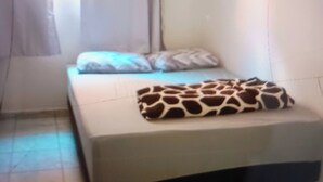 A bedroom with a bed, curtains, and a giraffe-patterned blanket.