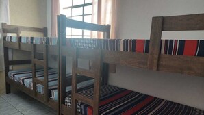 A dormitory room with bunk beds, a window with curtains, and a tiled floor.