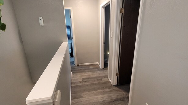 A hallway with a wooden floor, white walls, and a white door at the end. - ​Work Crew Special: Monthly Rates Full Kitchen & Laundry (Douglas)