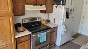A kitchen with wooden cabinets, a stainless steel stove, a white refrigerator, and a blue lantern on top. - ​Work Crew Special: Monthly Rates Full Kitchen & Laundry (Douglas)