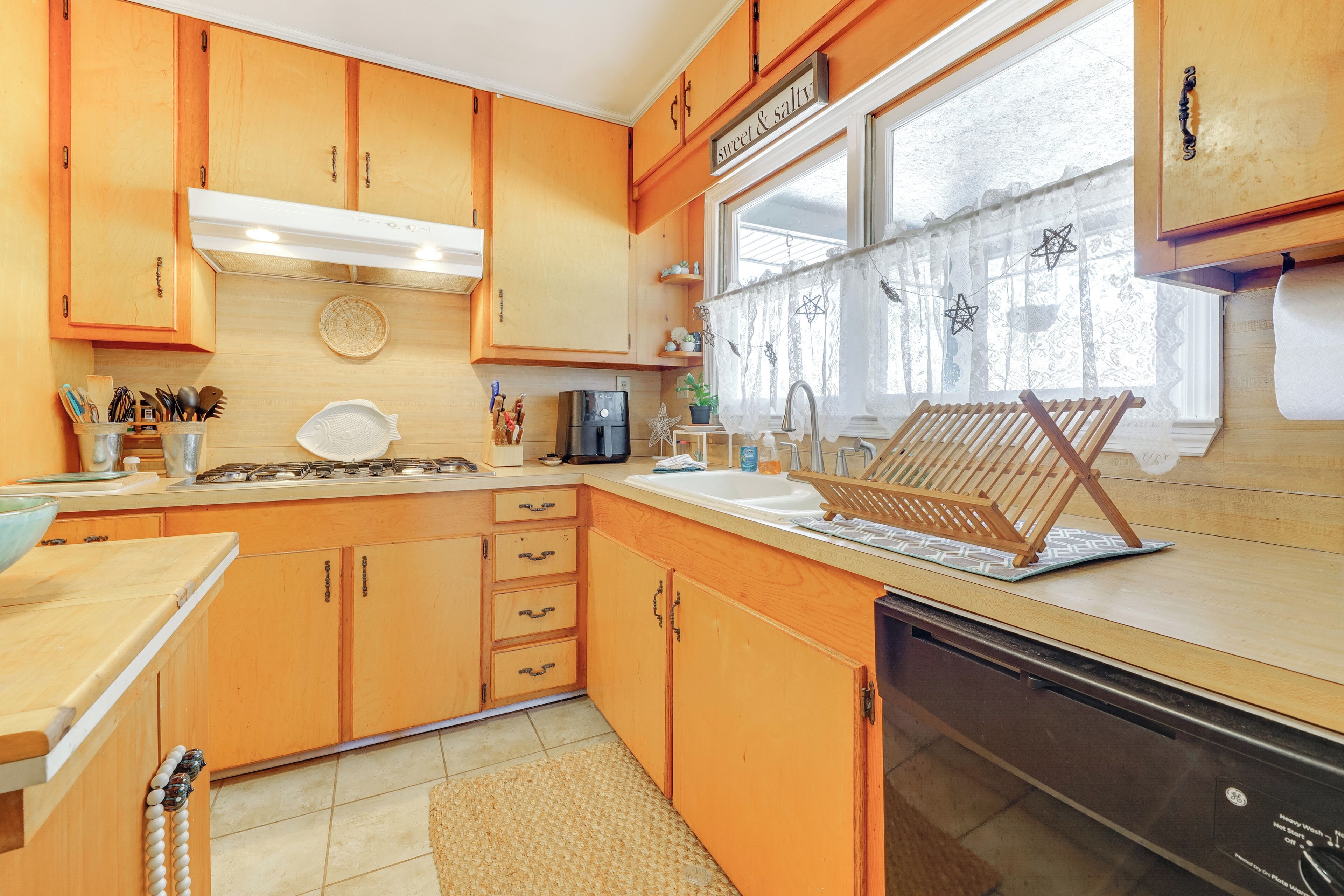 Una cocina con armarios de madera, una estufa, un fregadero y un lavavajillas.