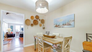 Un comedor con una mesa y sillas de madera, una cesta trenzada sobre la mesa y un cuadro en la pared.