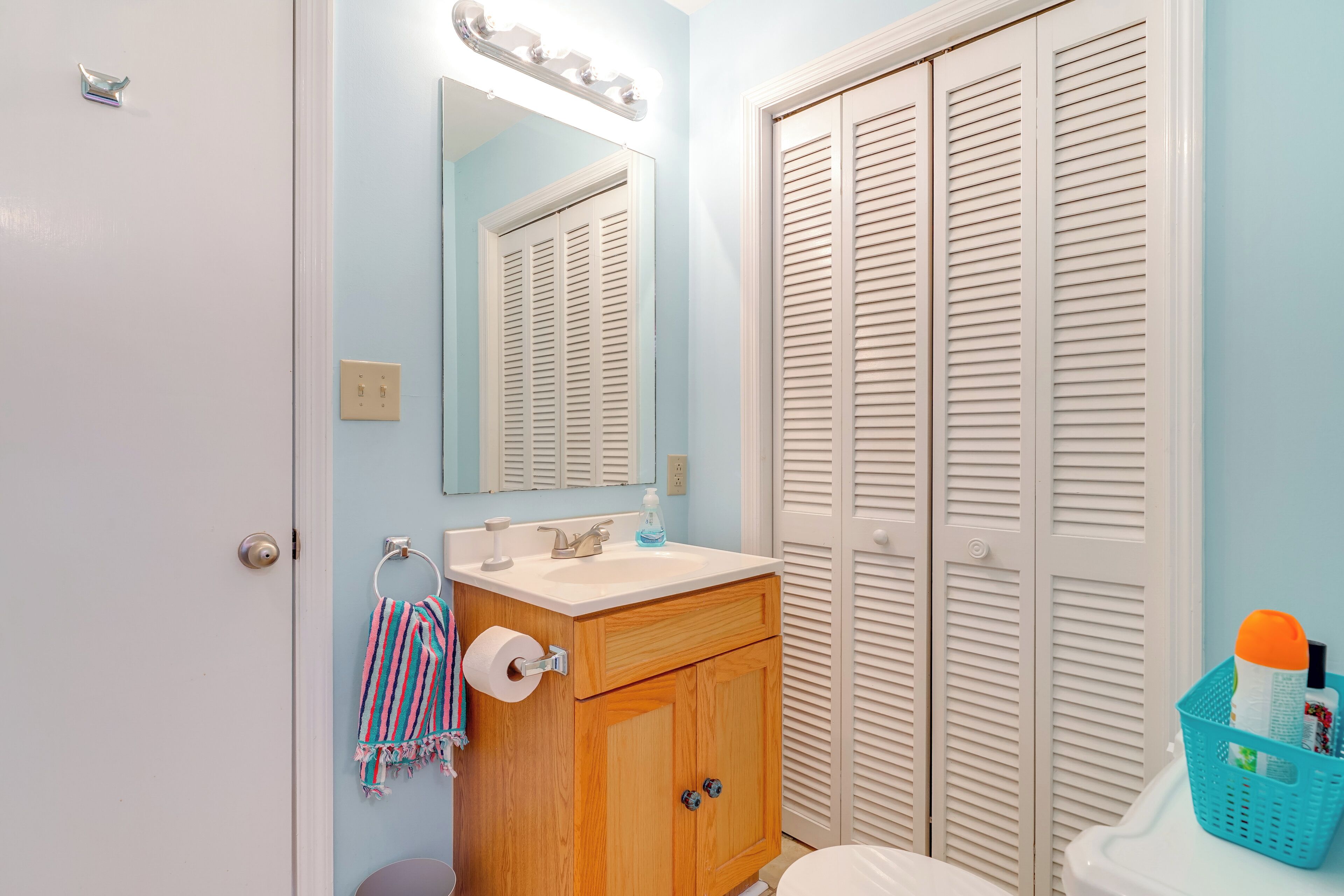 Une salle de bain avec un meuble-lavabo en bois, un évier, un miroir et des toilettes.