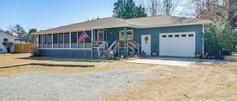 A single-story house with a covered porch, a garage, and a flag.