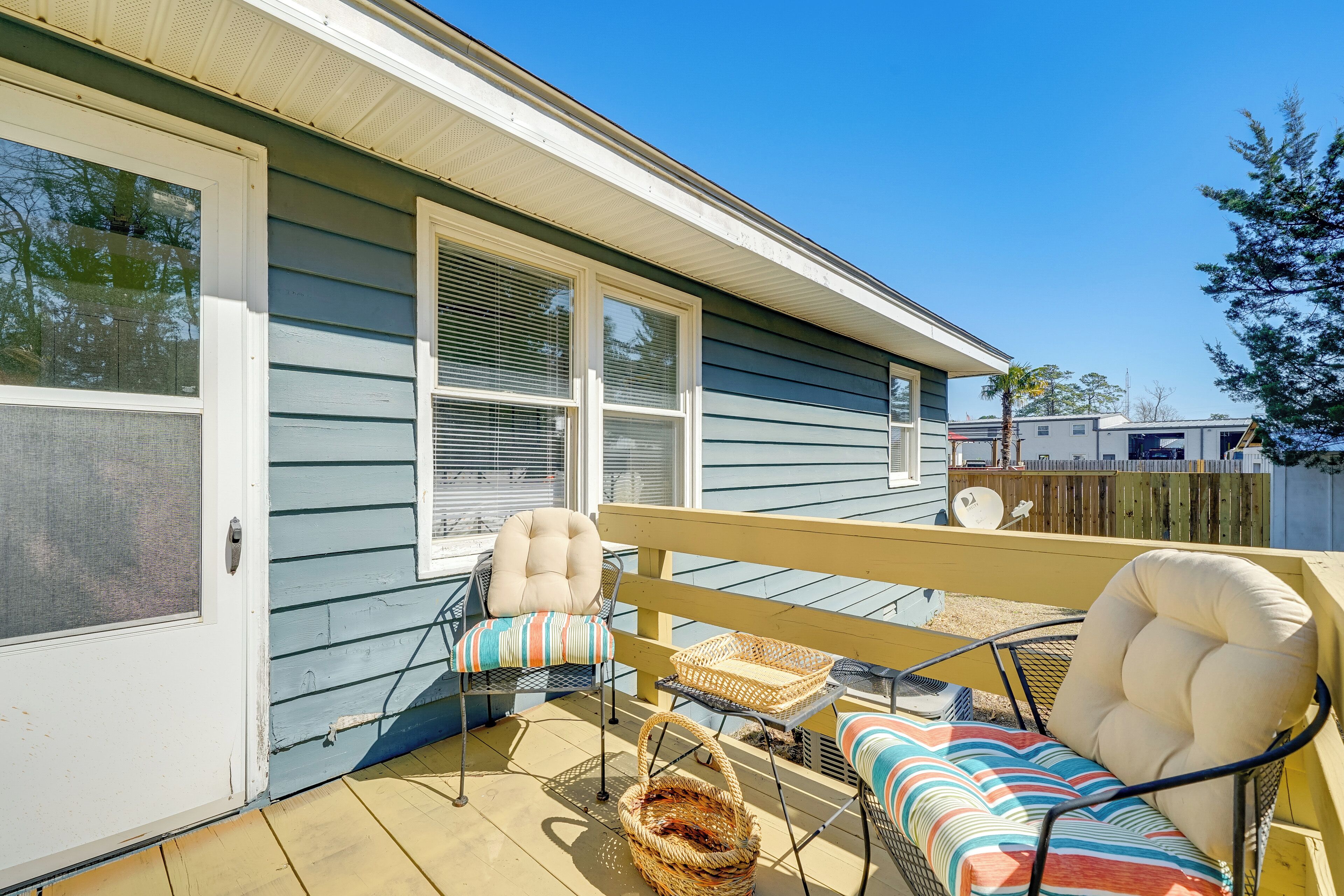 A covered patio with outdoor furniture, including a cushioned chair and a sofa with a striped cushion.