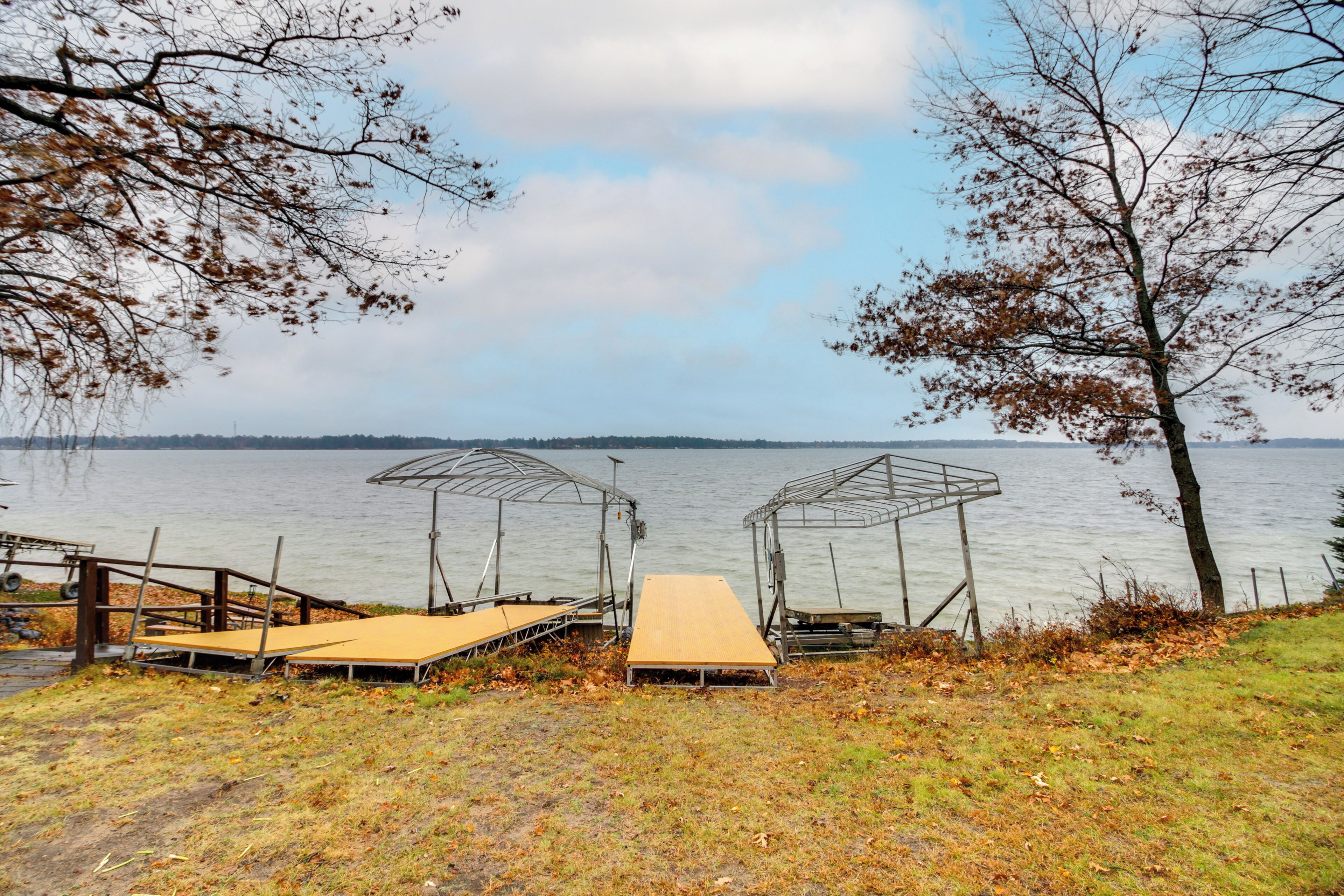 A lakeside deck with metal gazebos and a wooden platform.