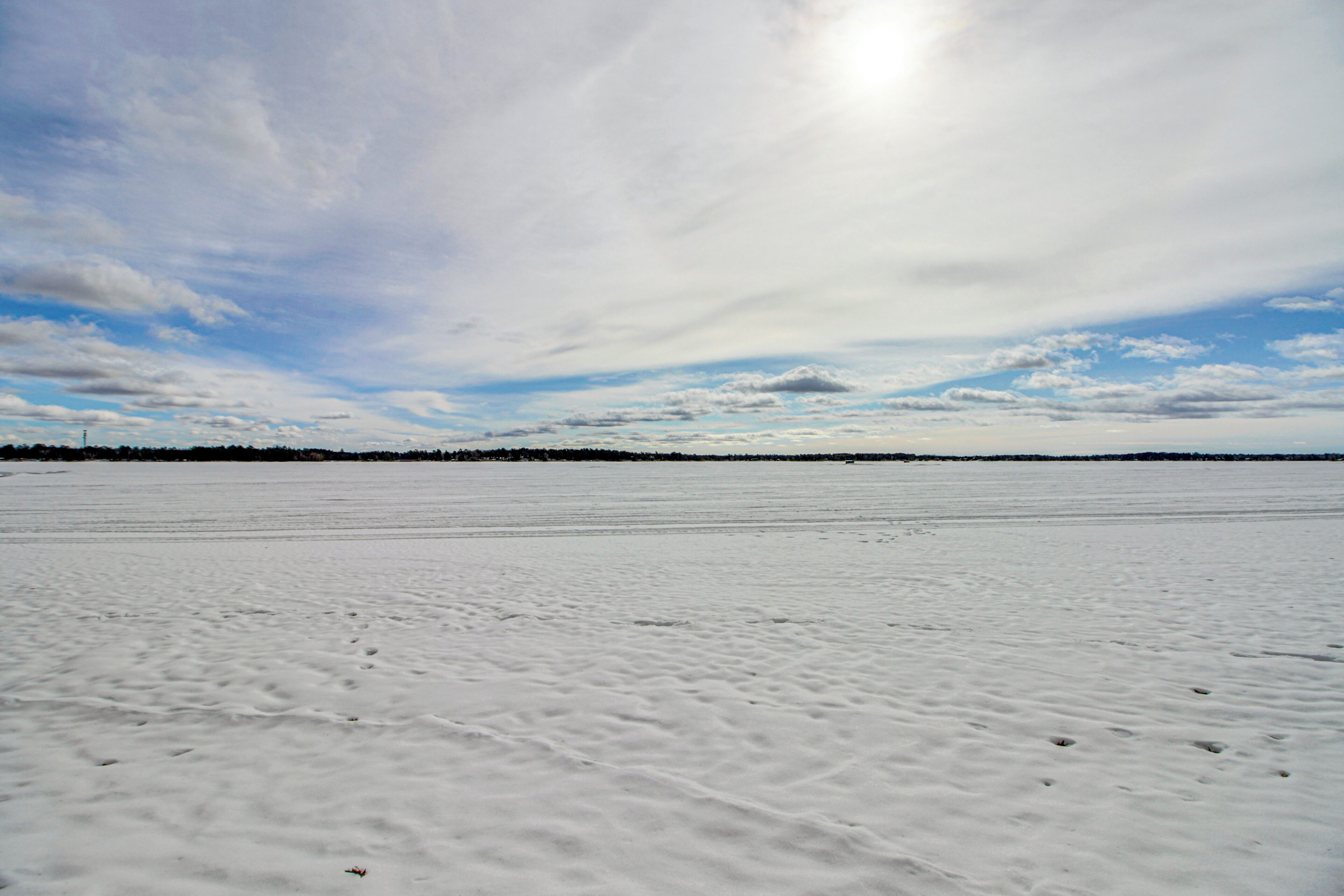 A vast, open snowy landscape with a clear sky and distant horizon.