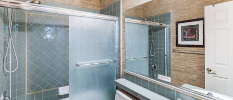 A modern bathroom with a glass shower enclosure, a large mirror, and a white sink.