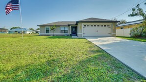 A single-story house with a garage, a well-maintained lawn, and an American flag. - 7 Mi to River District: Cape Coral Home w/ Lanai (Cape Coral)