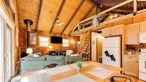 Un intérieur de chalet chaleureux comprenant un coin repas, une cuisine et une chambre à coucher située en mezzanine.
