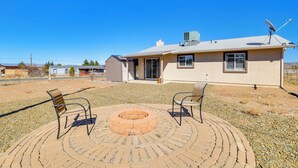 Una casa con un patio che include due sedie e un braciere circolare.