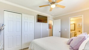Una camera da letto con un letto, una ventola a soffitto e una televisione appesa al muro.