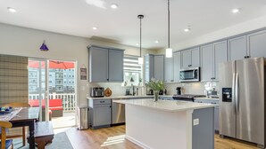 A modern kitchen with grey cabinets, stainless steel appliances, and a central island. - Walk to Dtwn: Waterfront Eastern Shore Townhome! (Cambridge)