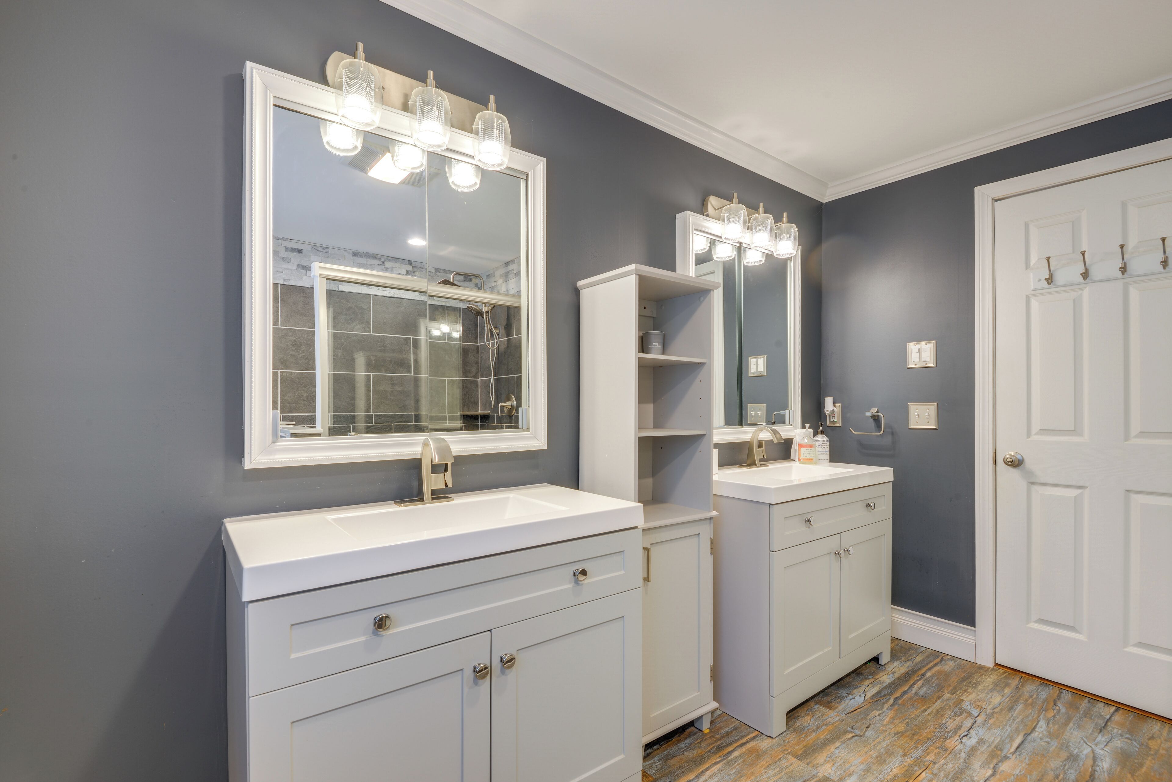 A bathroom with a large mirror, two sinks, and a white vanity.