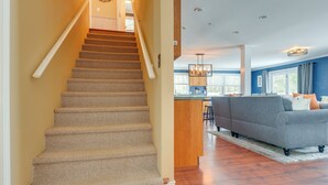 A staircase leading to a kitchen area with a gray sofa and wooden flooring.