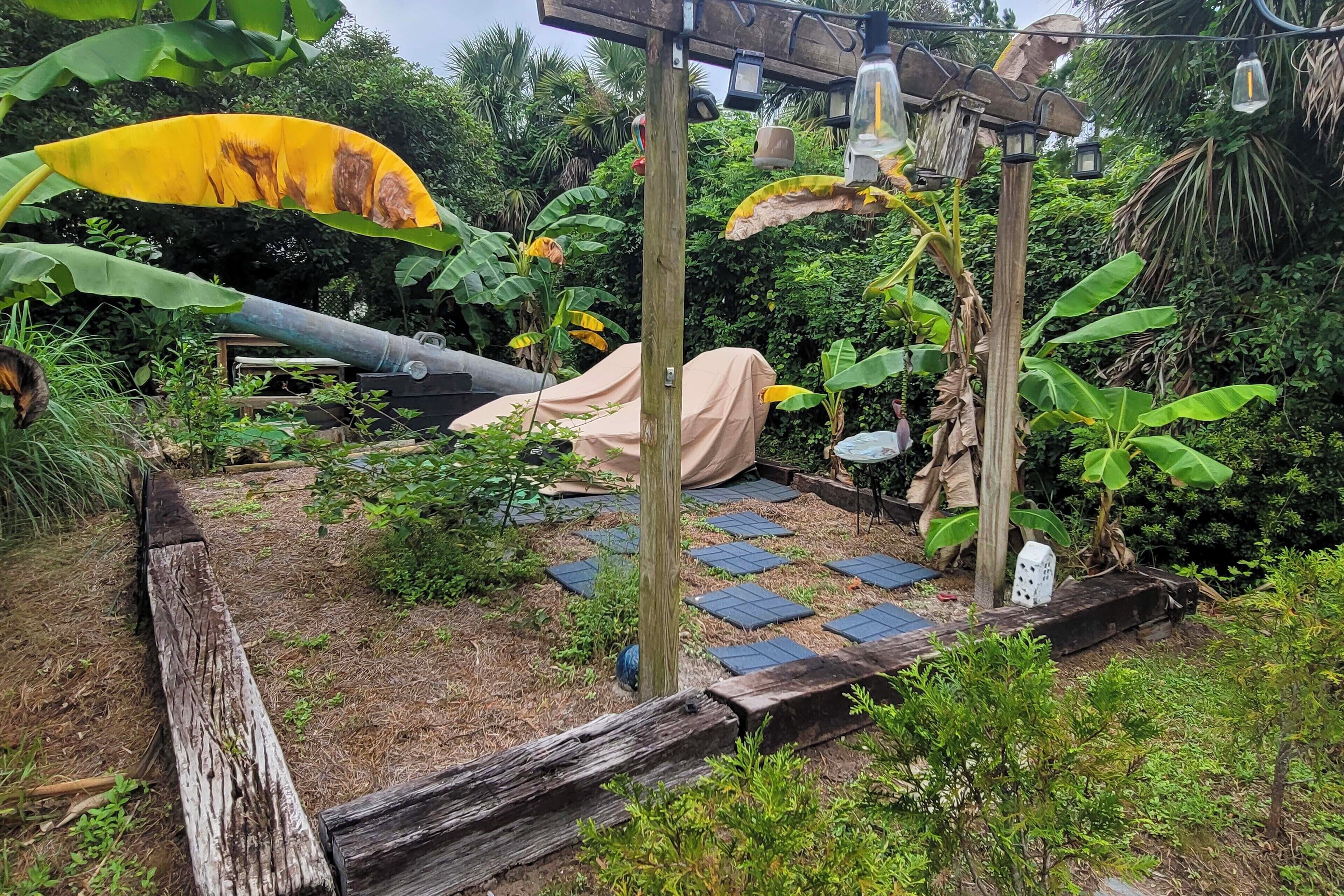 Un jardín con un porche de madera, paneles solares y una zona de estar cubierta.