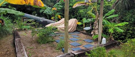 Un jardín con un porche de madera, paneles solares y una zona de estar cubierta.