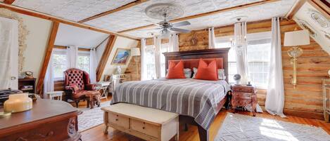 A bedroom with a large bed, wooden ceiling, and a chandelier.