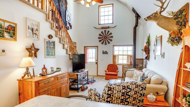 A spacious living room with a fireplace, a mounted deer head, and a staircase leading to another level. - 'red Barn Getaway' Chillicothe Countryside Home (Chillicothe)