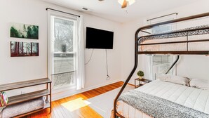 A bedroom with a bunk bed, a ceiling fan, a TV mounted on the wall, and a window with blinds. - Mins to Local Attractions: Pet Friendly w/ Yard! (Casey)