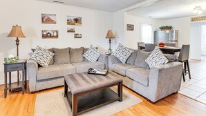 A modern living room with a grey sofa set, a coffee table, and a dining area with a table and chairs. - Mins to Local Attractions: Pet Friendly w/ Yard! (Casey)