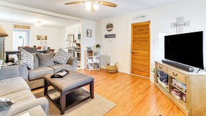 A living room with a sofa, coffee table, TV stand, and a ceiling fan. - Mins to Local Attractions: Pet Friendly w/ Yard! (Casey)