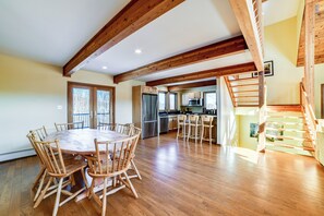 A spacious kitchen with wooden beams, a dining area with a round table and chairs, and a staircase. - Golf, Fish & Ski: Retreat w/ Game Room in Thompson (Thompson)