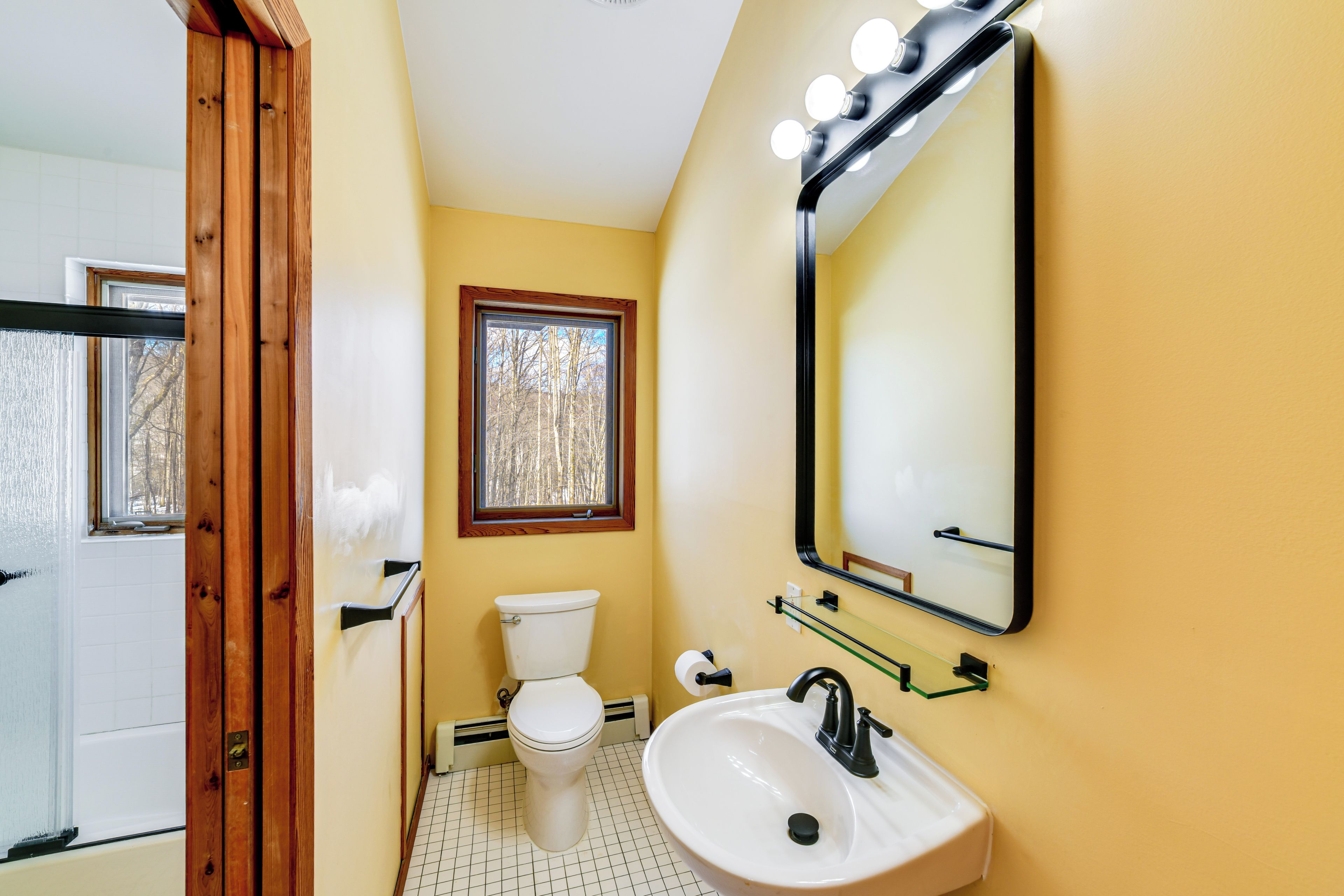 Un baño con inodoro, lavabo, espejo e iluminación.