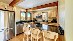 A modern kitchen with wooden cabinets, stainless steel appliances, and a central island with bar stools. - Golf, Fish & Ski: Retreat w/ Game Room in Thompson (Thompson)