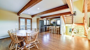 A spacious kitchen with wooden beams, a dining area with a round table and chairs, and a staircase. - Golf, Fish & Ski: Retreat w/ Game Room in Thompson (Thompson)