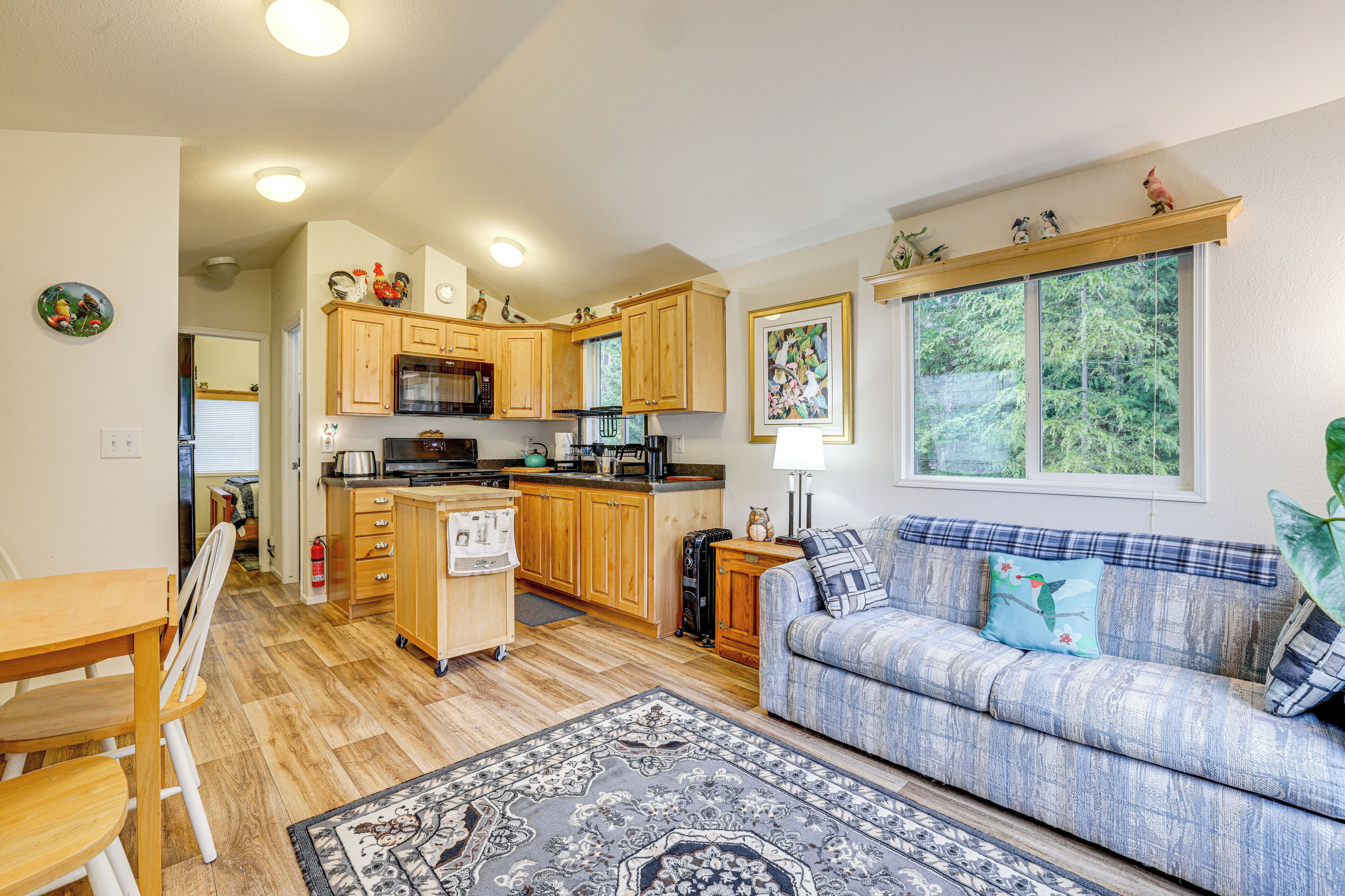 A compact kitchen with wooden cabinets, a dining table, and a sofa.
