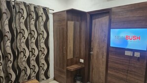 Ein Schlafzimmer mit einem Bett, einem Kleiderschrank, einem Fernseher und einem Vorhang.