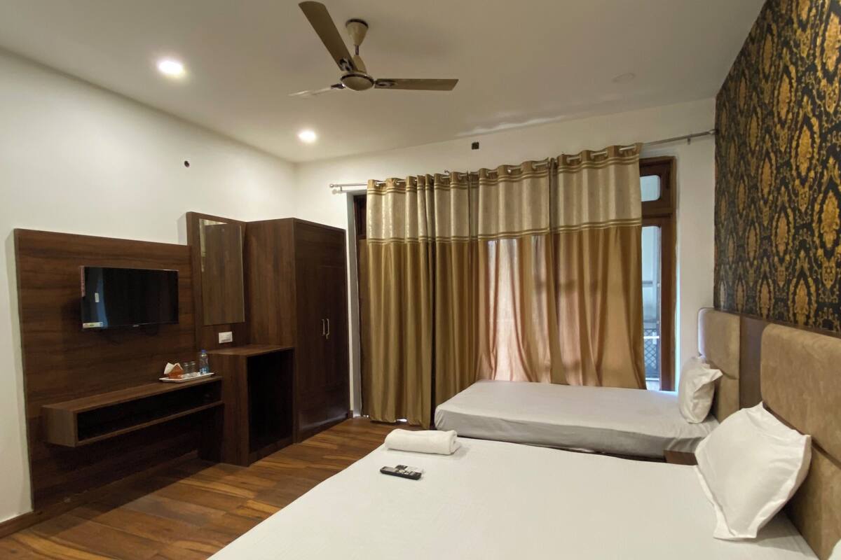 A hotel room with a bed, a TV, a desk, and a ceiling fan.