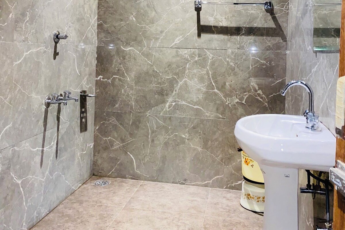 Une salle de bain avec une douche, un lavabo et des murs en marbre.