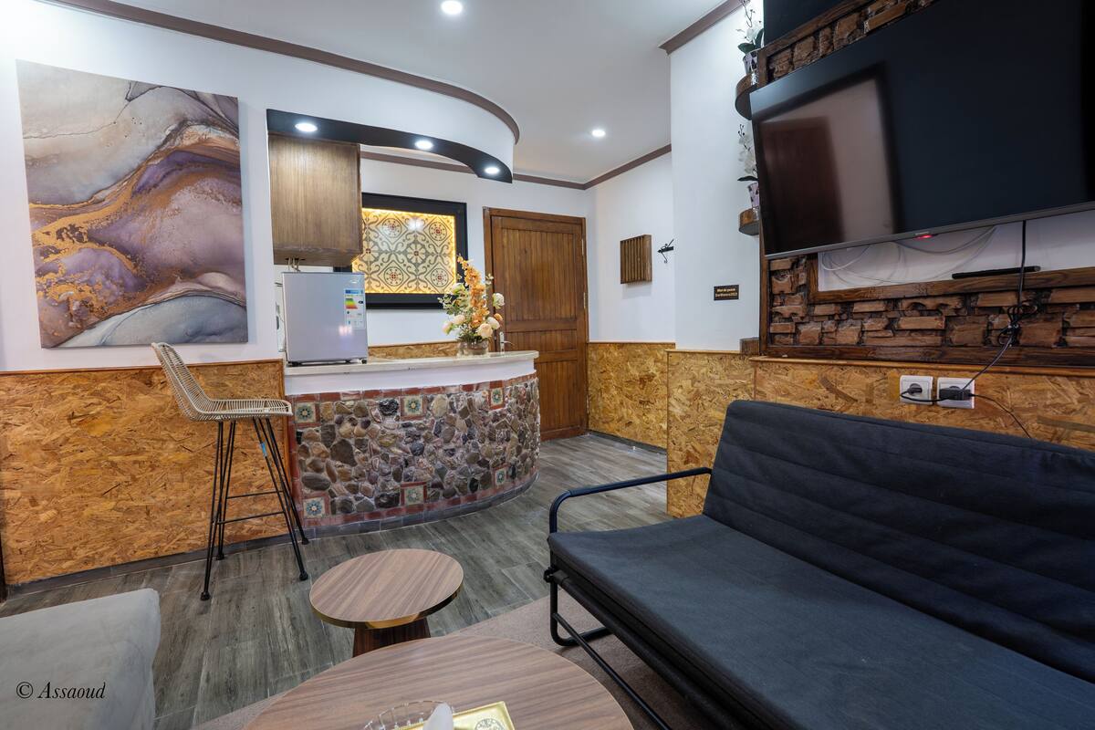 A modern kitchen with a stone backsplash, a wooden counter, and a built-in TV.