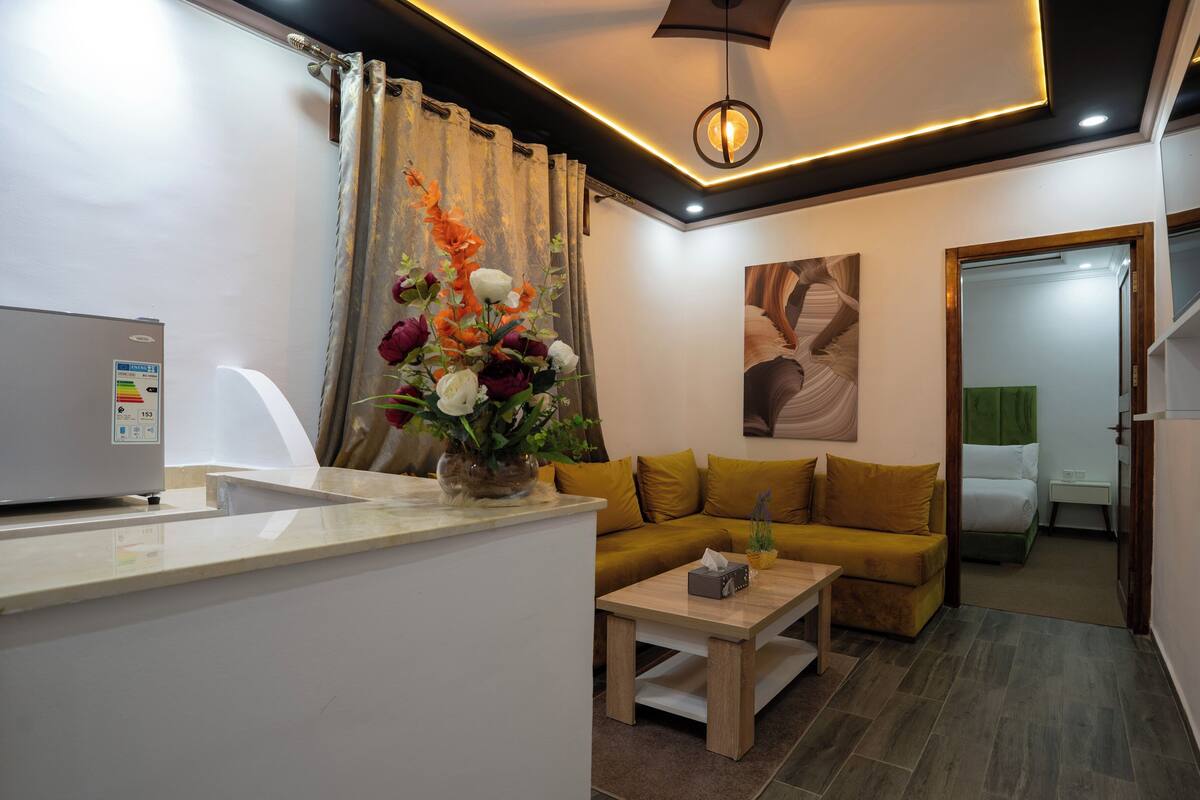 A modern living room with a sofa, a coffee table, and a decorative vase with flowers.
