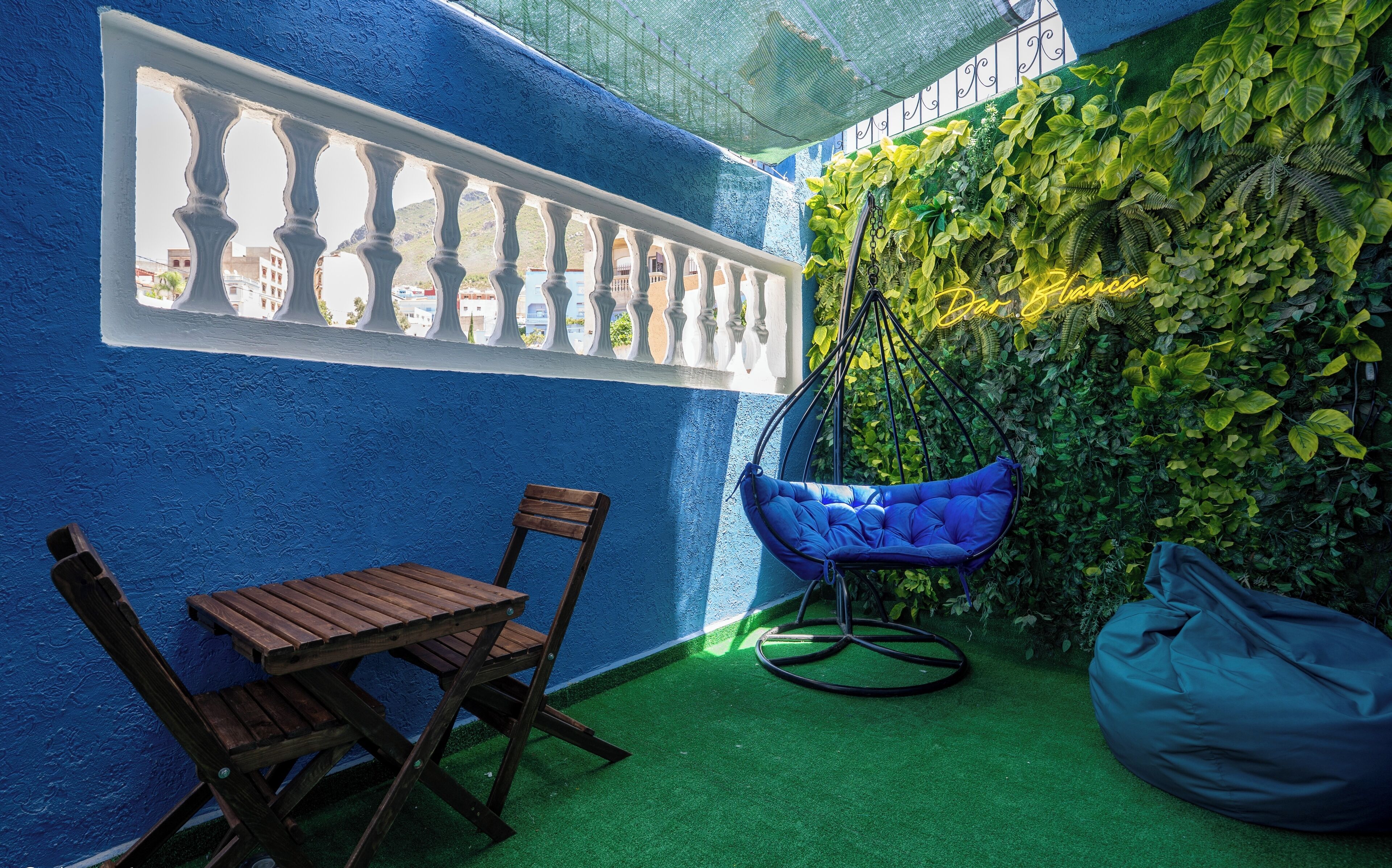 A blue-walled room with a hanging chair and a wooden table.