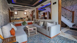 A modern living room with a grey sofa, a small coffee table, and a kitchen in the background. - DAR BLANCA (Chefchaouen)