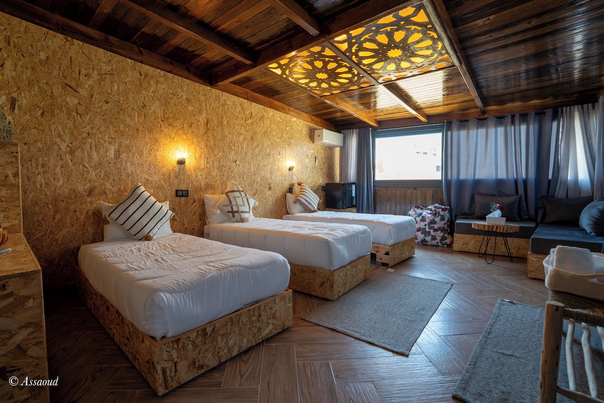 A room with two wooden beds, a sofa, and a television.