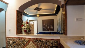 A reception area with a stone wall, a decorative ceiling, and a floral arrangement. - DAR BLANCA (Chefchaouen)
