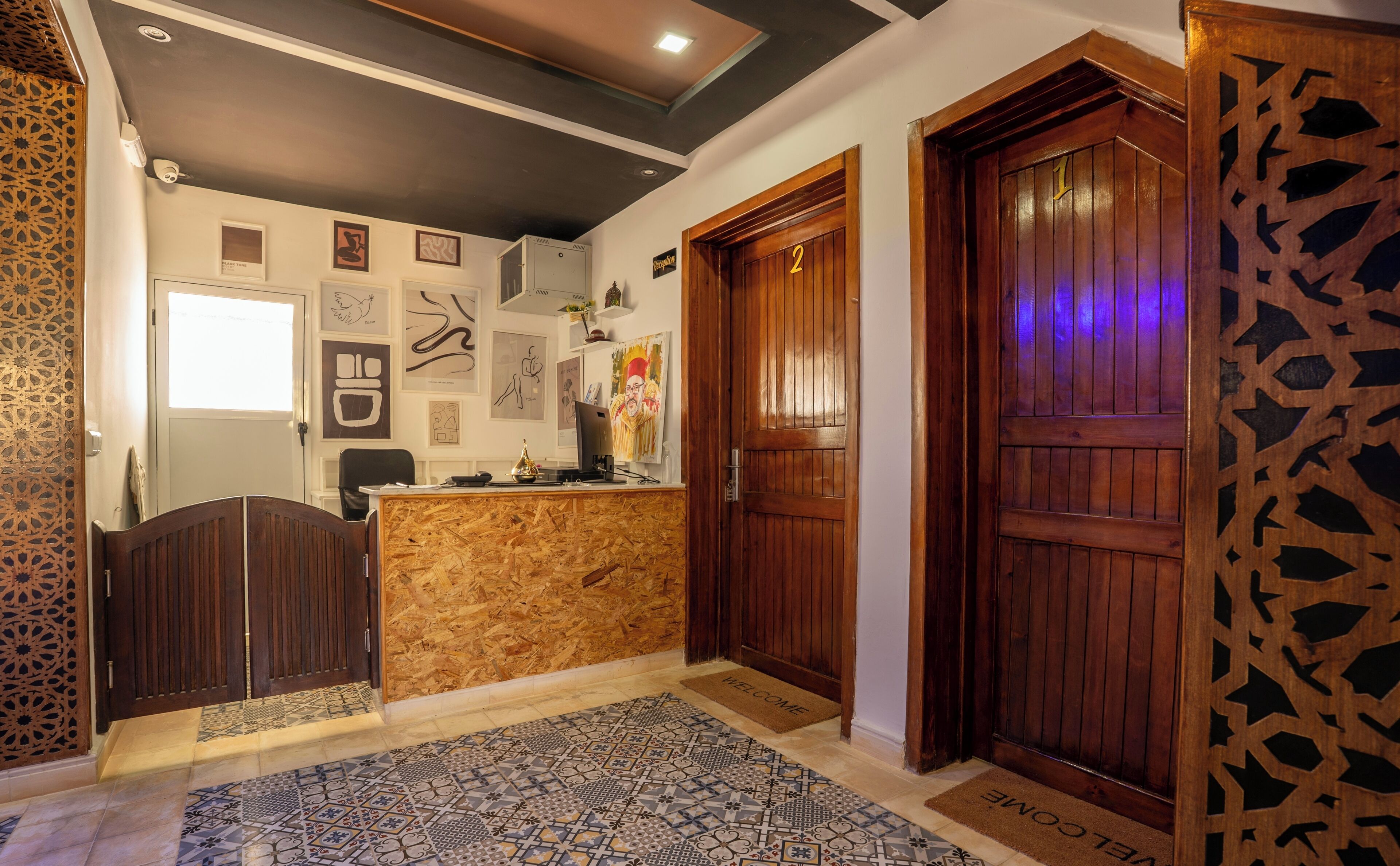 A reception area with a wooden desk, a computer, and framed artwork on the wall.