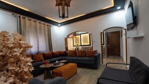 A modern living room with a sectional sofa, ottoman, and a small round table. - DAR BLANCA (Chefchaouen)